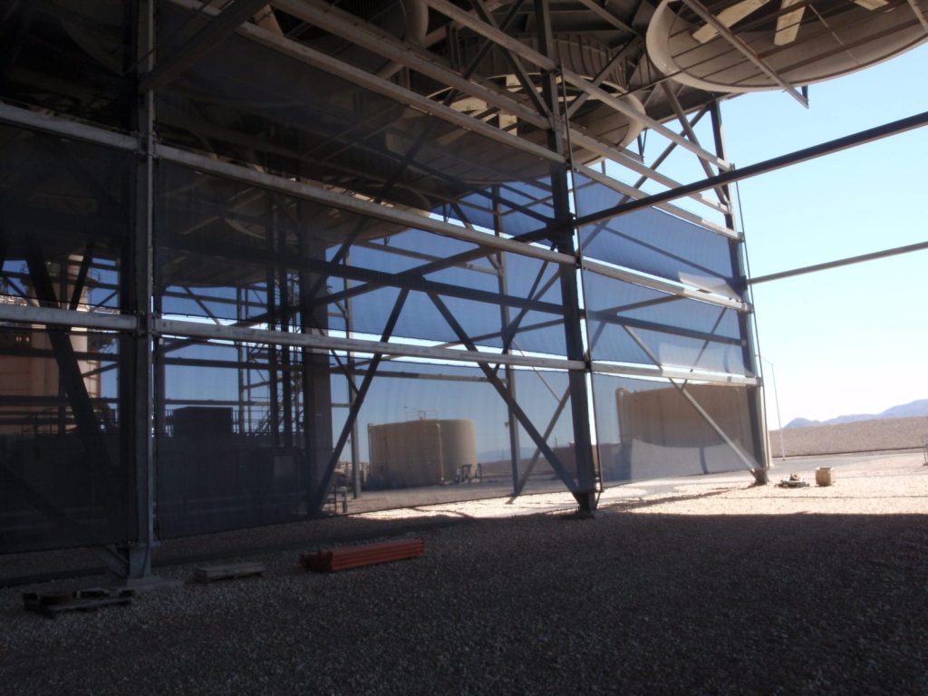 A large industrial structure with metal framework and blue mesh panels