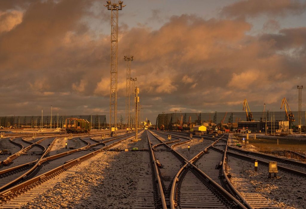 Railway tracks crisscross under a dramatic, golden-lit cloudy sky