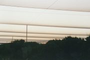 Parallel horizontal beams against a dusky sky with silhouetted trees below