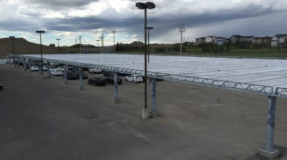 A parking lot with a large metal canopy and cloudy sky overhead