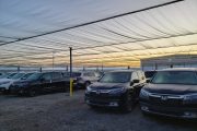 Cars parked under a large, translucent canopy at sunset
