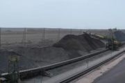 A panoramic view of an industrial site with large piles of coal and wind fences