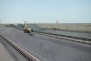 Aerial view of coal piles and machinery at an industrial site with wind fences