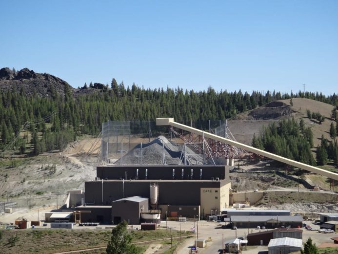 A large industrial facility with a conveyor belt and dust control fence