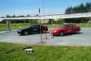 Two cars parked under a large white canopy structure in a grassy area