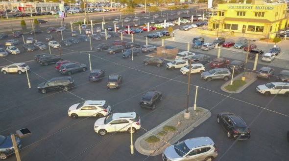 An aerial view of a car dealership parking lot with numerous vehicles and a Southwest Motors building