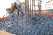 Two construction workers are bending rebar on a reinforced concrete foundation