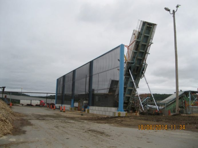 A large industrial structure with a conveyor belt leans against a building