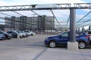 A parking lot with a black mesh canopy covering rows of parked cars