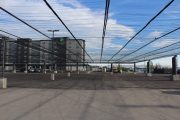 A parking lot with a large overhead netting structure supported by concrete pillars
