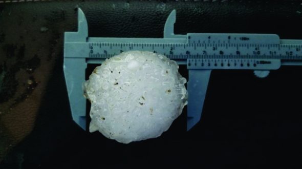 A large hailstone being measured with calipers