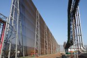 Large industrial wind fence with metal framework and adjacent conveyor system