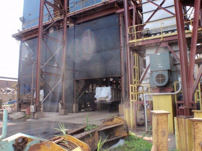 Industrial site with metal structures, machinery, and some smoke or dust in the air