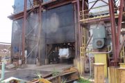 Industrial site with metal structures, machinery, and some smoke or dust in the air