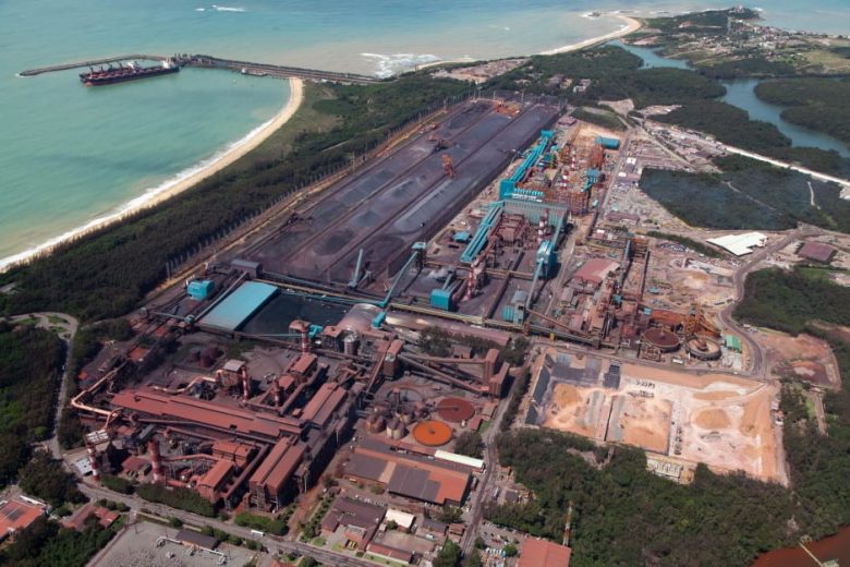 Aerial view of an industrial complex near a coastline with storage areas and machinery