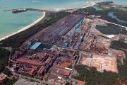 Aerial view of an industrial complex near a coastline with storage areas and machinery