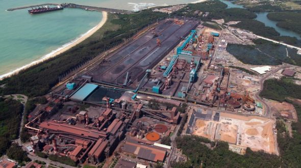 Aerial view of an industrial complex near a coastline with storage areas and machinery