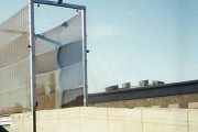 A tall, metal-framed wind fence with fabric panels stands against a clear sky