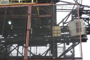 Industrial structure with metal framework and mesh panels, featuring yellow railings and lighting