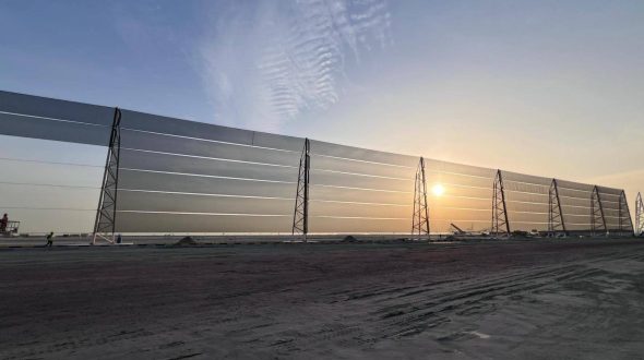 Large industrial wind fence with metal framework at sunset on a construction site