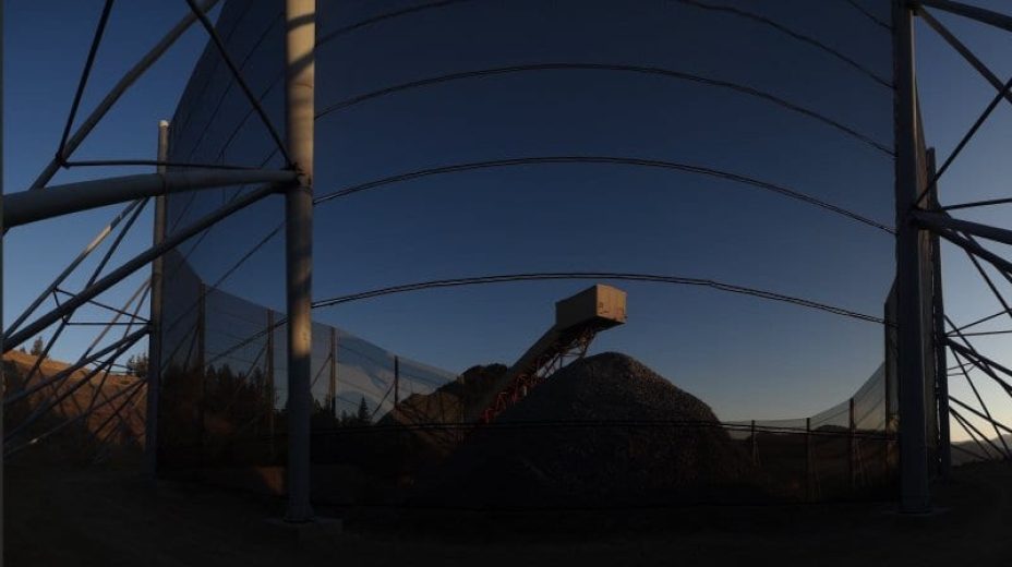 A large industrial structure with netting and a pile of material beneath it