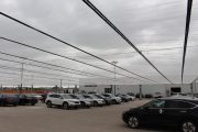Cars parked under a large translucent canopy on a cloudy day