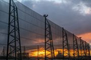 A tall metal fence structure with netting against a dramatic sunset sky