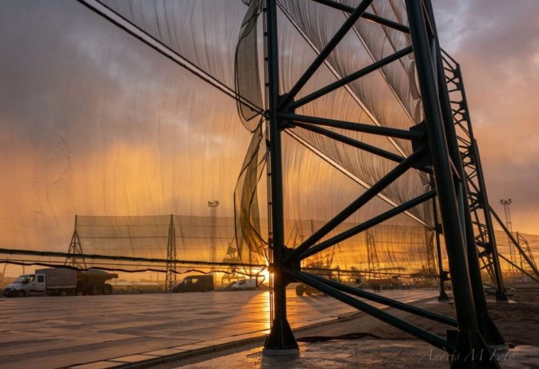 A large industrial wind fence with a sunset in the background