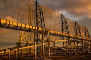 Large industrial structure with metal framework and mesh panels, set against a sunset sky