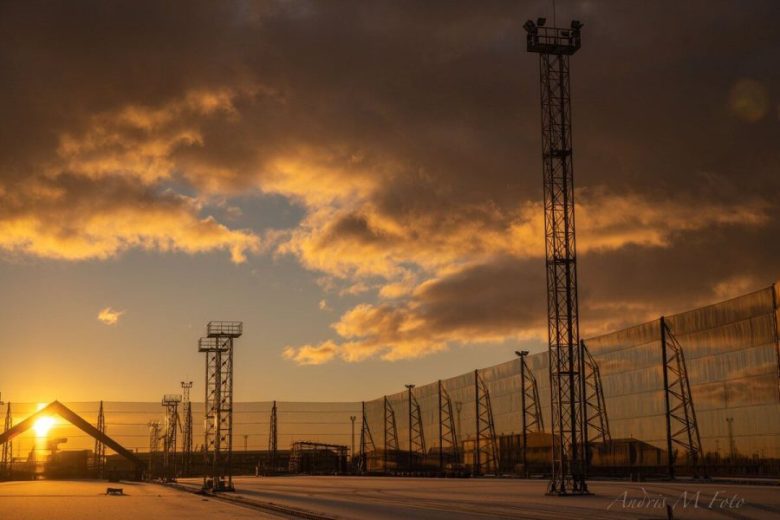 Sunset illuminates industrial wind fences and tall towers at a facility