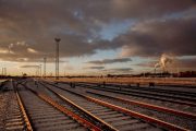 Railway tracks stretch into the distance under a dramatic, cloudy sky at sunset