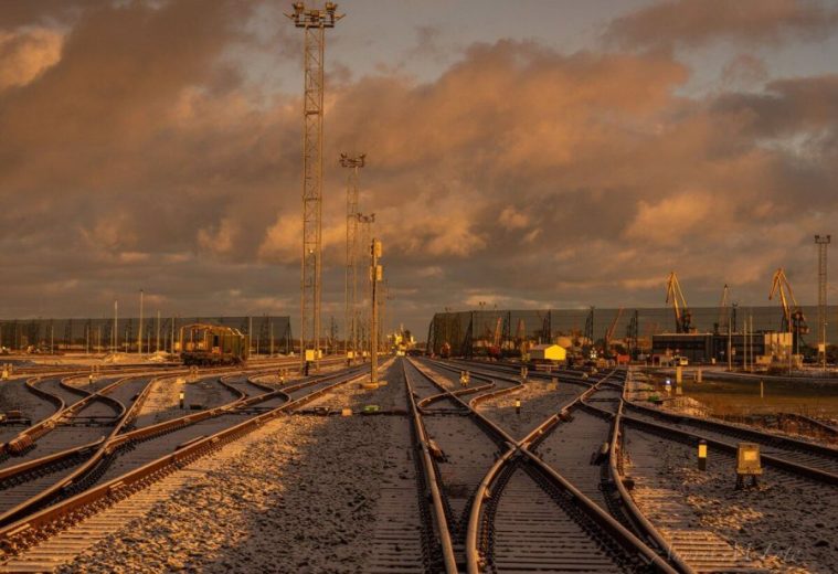Railway tracks in a snowy industrial area under a dramatic, orange-lit sky
