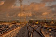 Railway tracks in a snowy industrial area under a dramatic, orange-lit sky