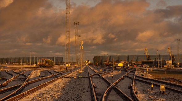 Railway tracks crisscross under a dramatic, golden-lit cloudy sky