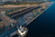 Aerial view of a port with cranes, a docked ship, and industrial structures