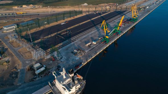 Aerial view of a port with cranes, cargo ship, and railway tracks