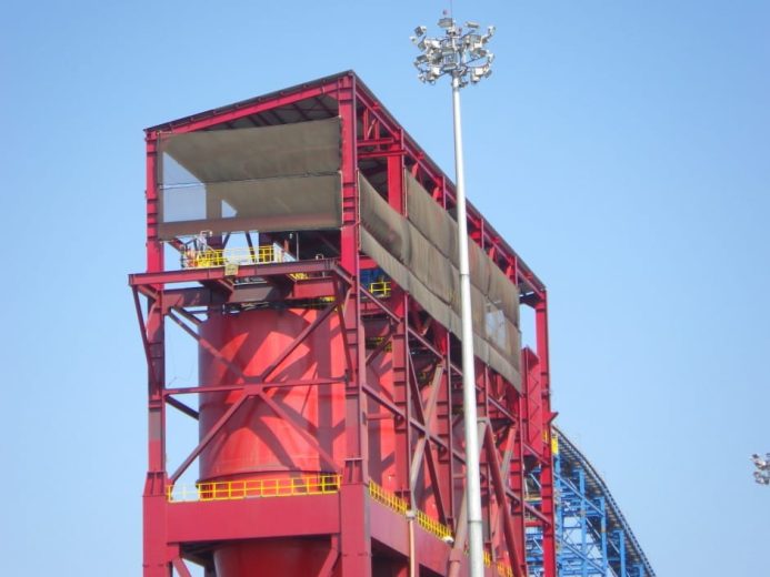 A large red industrial structure with a tall light pole beside it