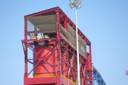 A large red industrial structure with a tall light pole beside it
