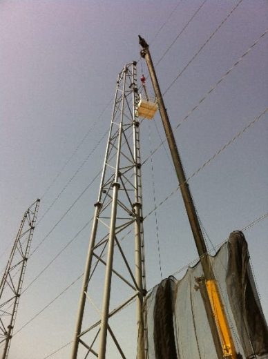 A tall metal tower with a crane lifting equipment against a clear sky