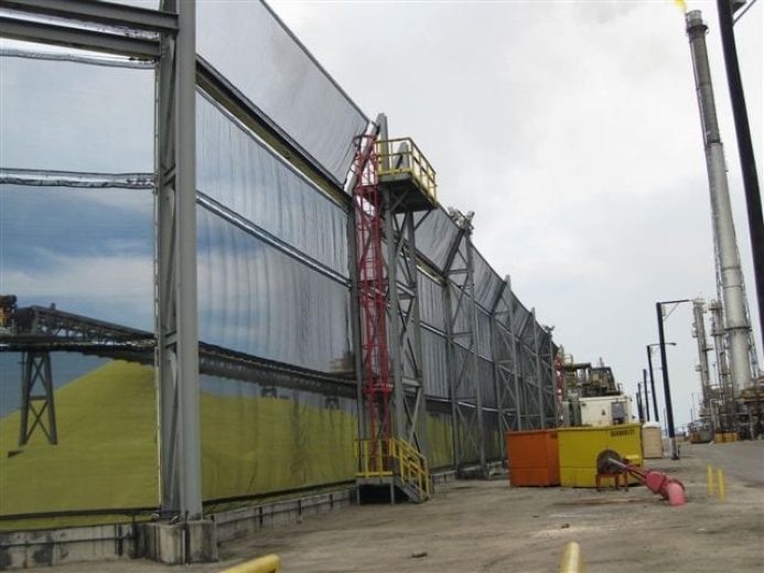 A large industrial wind fence with a red staircase and yellow platform