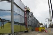 A large industrial wind fence with a red staircase and yellow platform